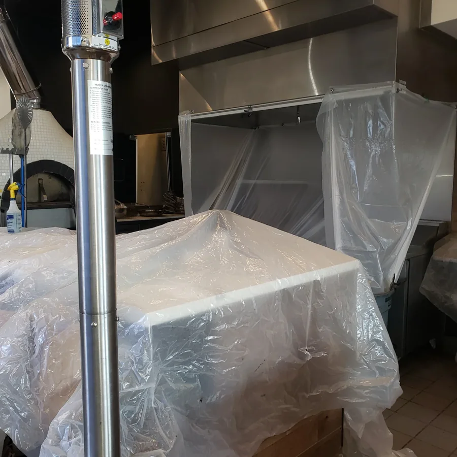 Commercial cooking equipment protected with plastic during cleaning preparation