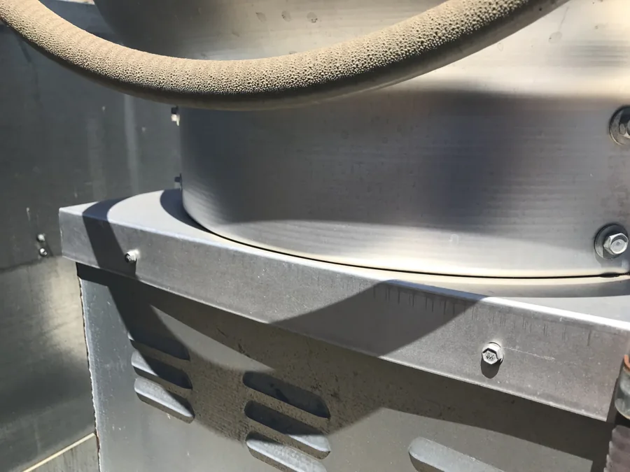 Close-up of hinge hardware on a rooftop exhaust fan