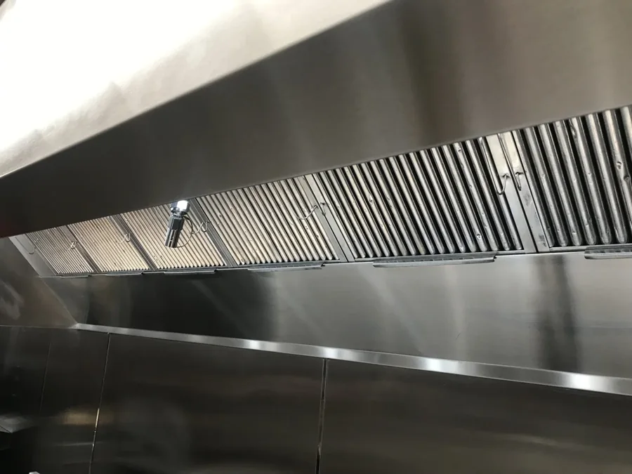 Clean stainless-steel exhaust hood above a commercial cooking line